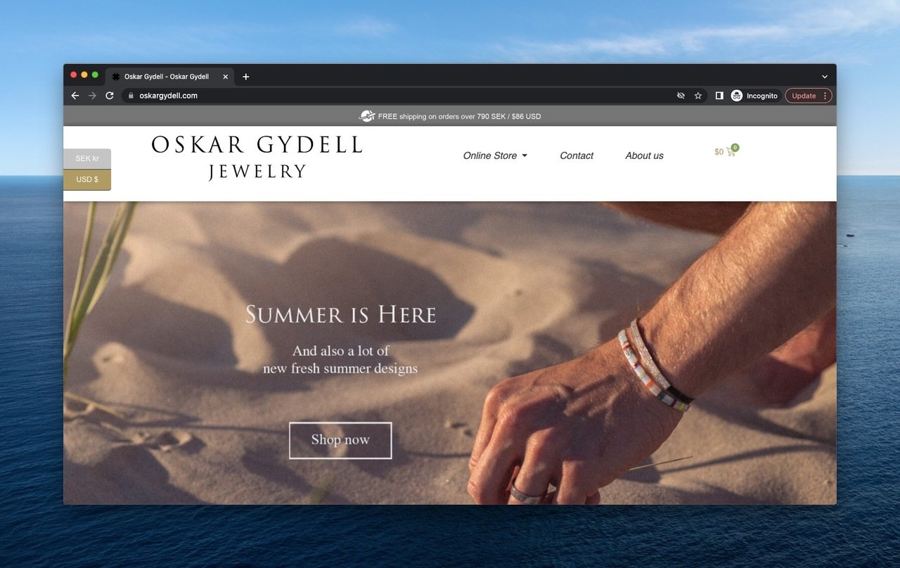 a hand wearing Oskar Gydell bracelets touching the sand