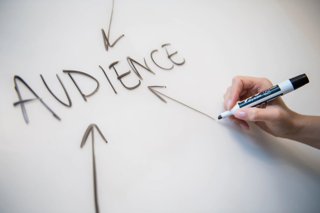 audience stock photo showing a hand drawing arrows pointing at the "audience" word written on a whiteboard