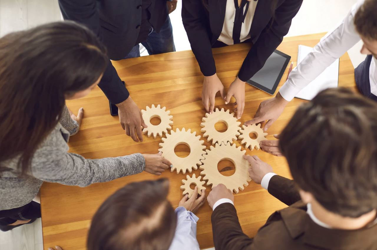 a group of knowledge workers around a table collaborating and showing how software integration works with the help of wooden gearweels