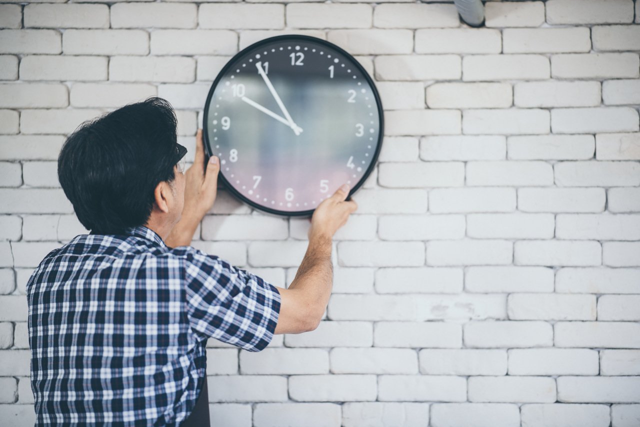 a man holding the clock on the wall to locate