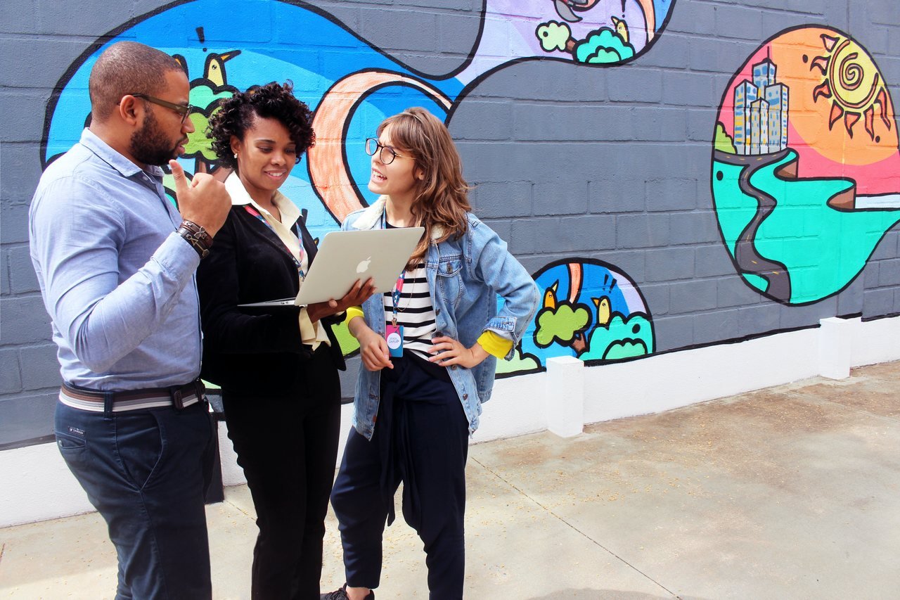 three people discussing an issue on a laptop