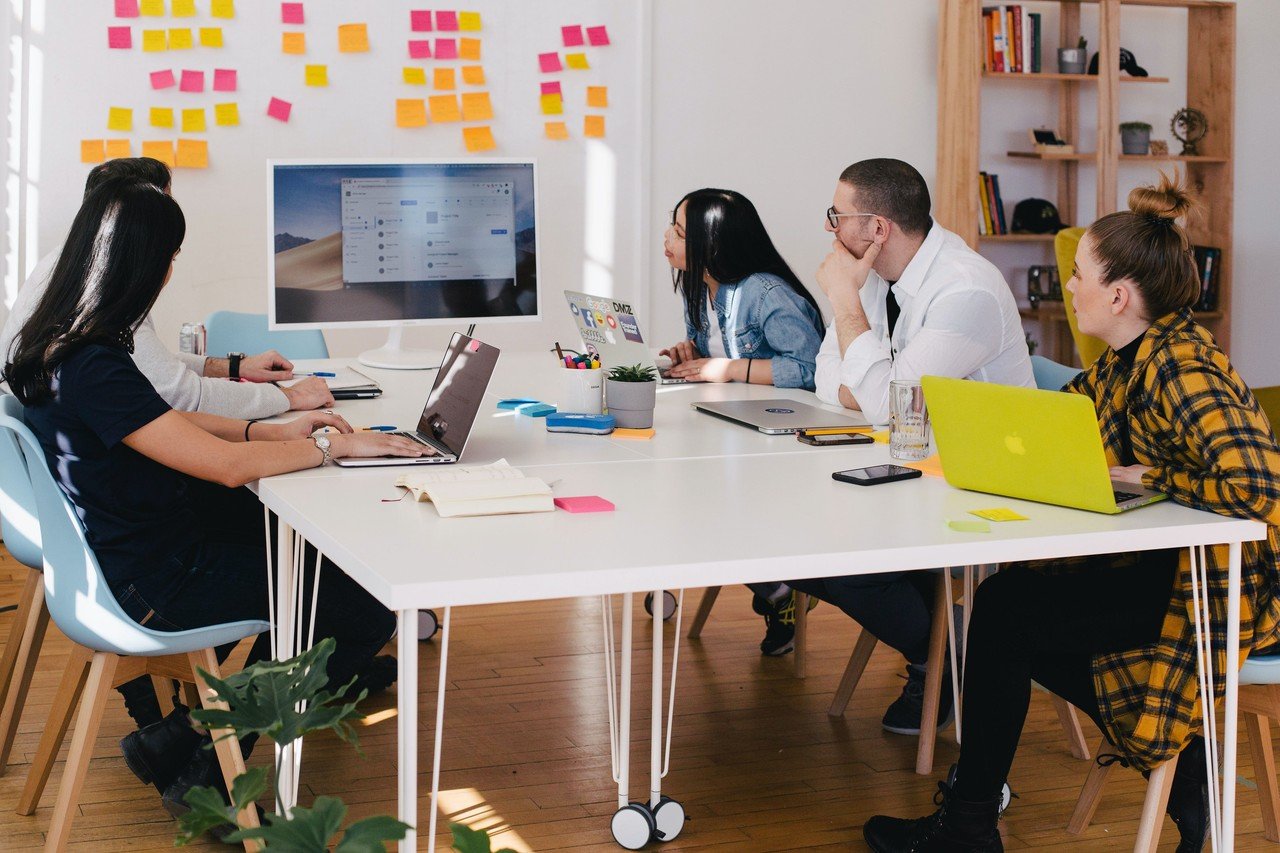 a group of people making a meeting around the table watching the white board