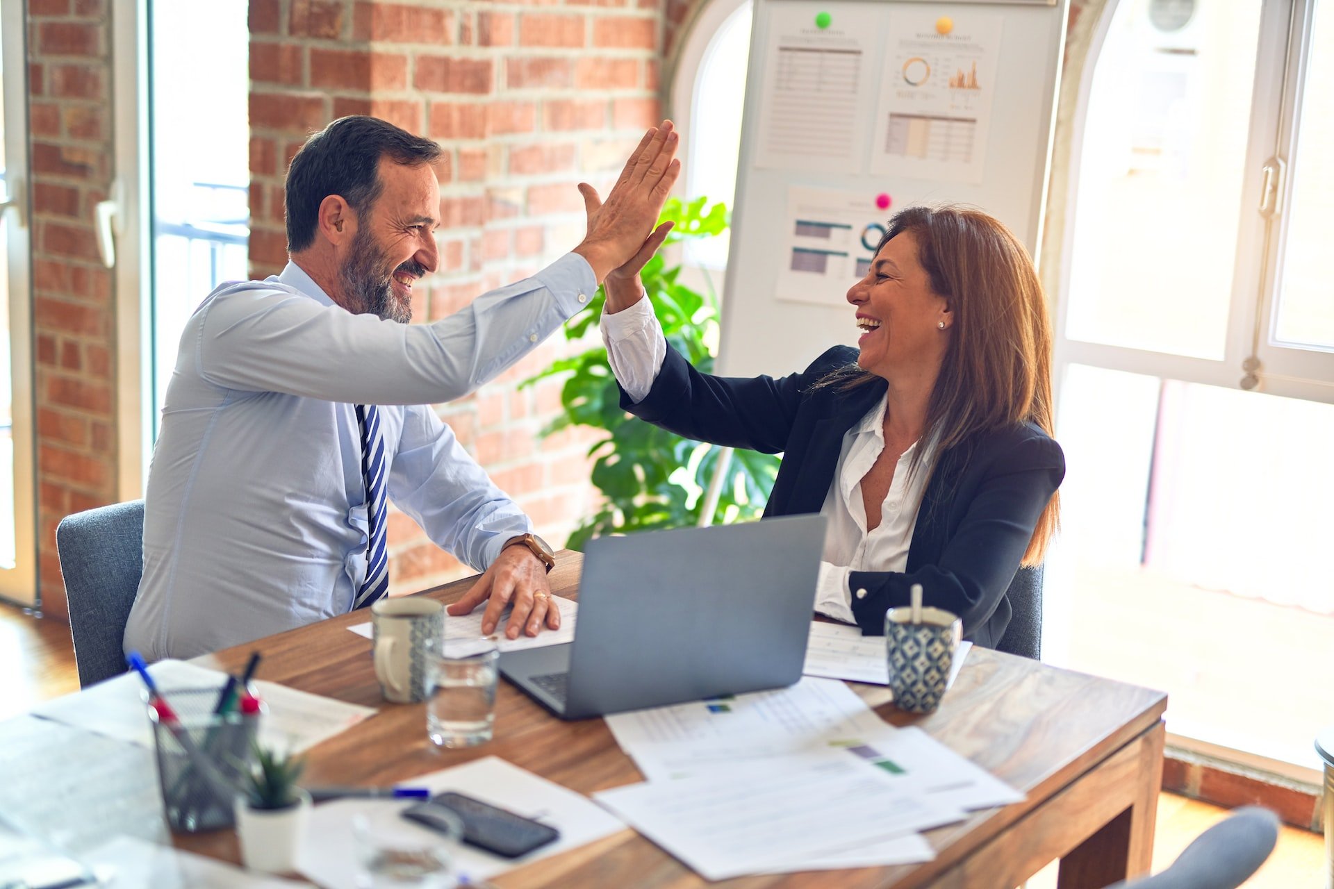 coworkers working together with smiles on thier faces and giving high fives at the office