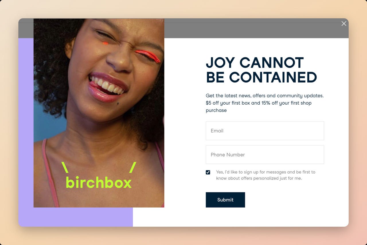 Birchbox SMS popup example with a picture of a happy girl smilling on the left side and a bold text on top left side that says “Joy Can Not Be Contained” with a call to action that says "submit"