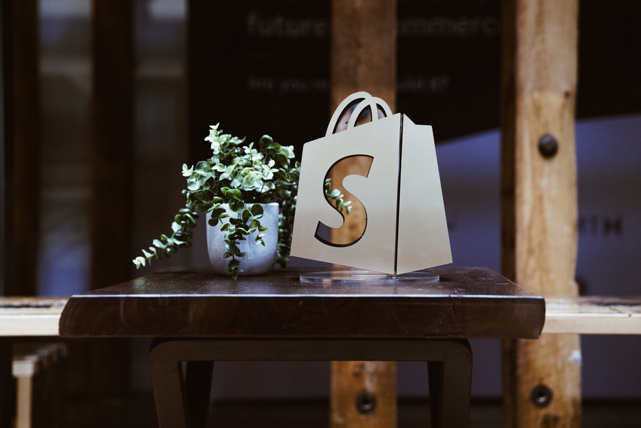 a Shopify logo with a plant on a table