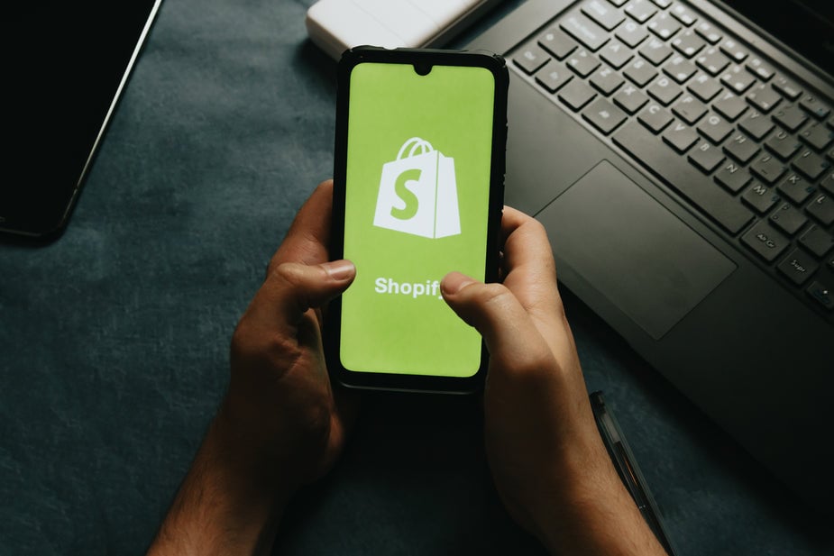 an image of a Shopify page on a mobile phone and a laptop in the background