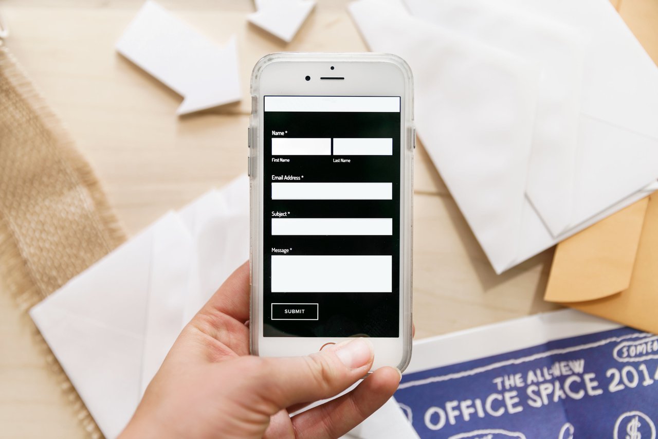 a phone displaying mobile contact us form and envelopes at the background