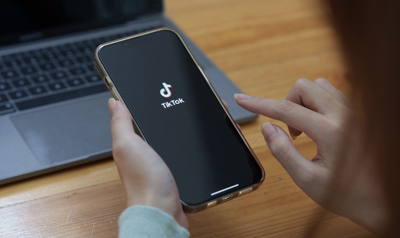 hands hold a cellphone showing the tiktok logo