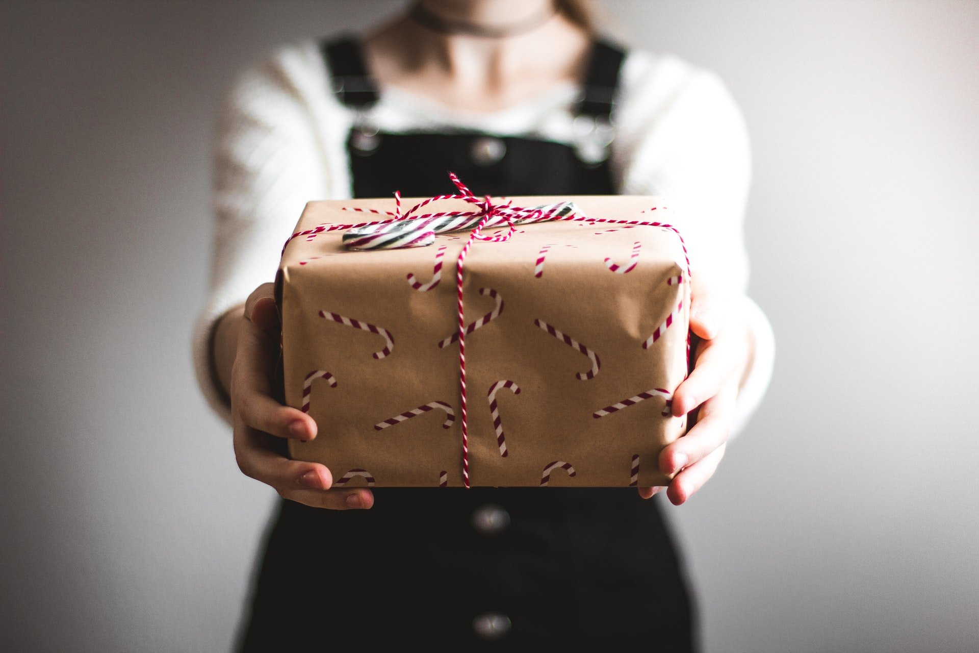 a girl wearing an overall showing a brown gift box with Christmas decorations