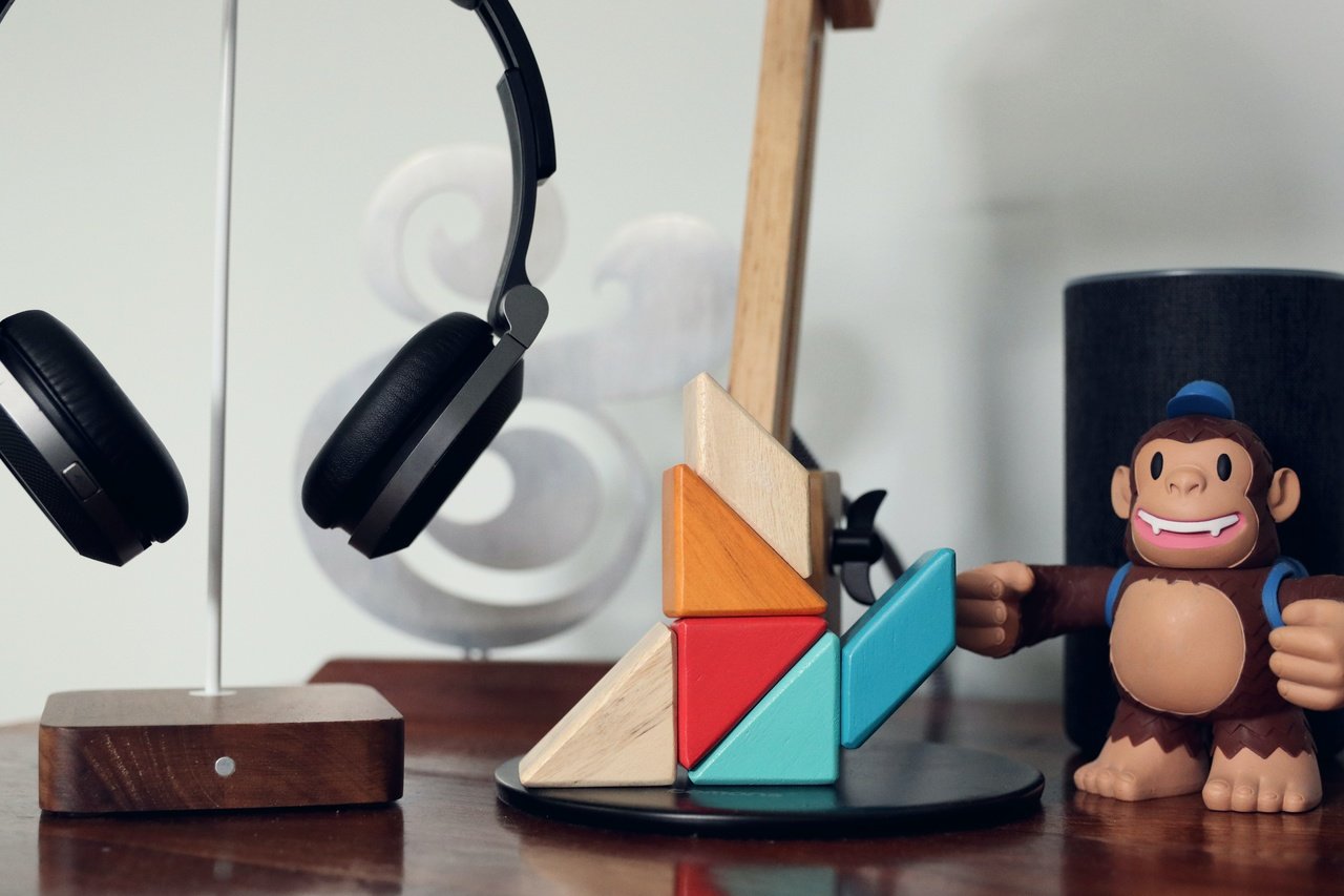 a desk with a wooden mailchimp monkey and a headphones