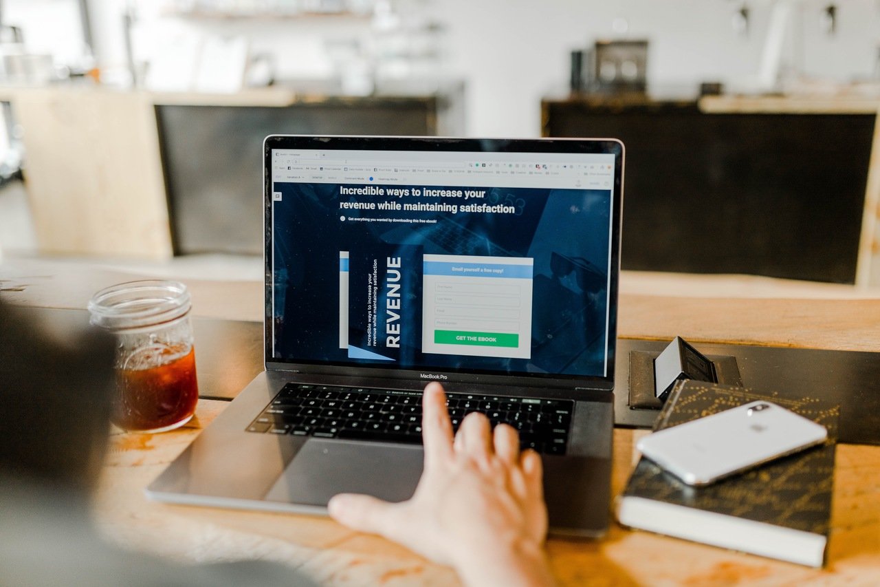 a hand working with a laptop on a desk that is showing a saas revenue