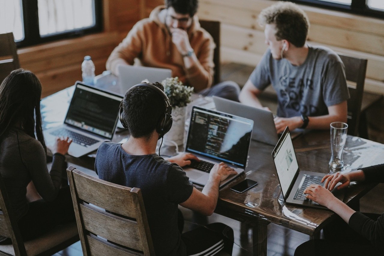 people working together with MacBooks on a table