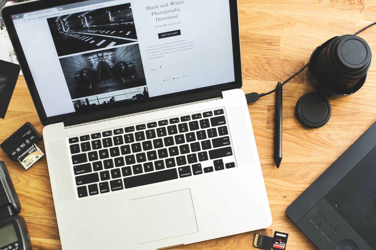 a laptop, a pen, mouse pad, disks on a table