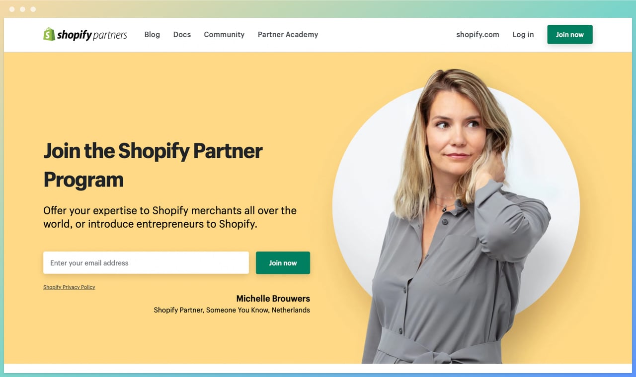 shopify partners homepage with the headline on the left with an email box underneath, and a woman caressing her hair wearing a grey shirt looking away on the rigt