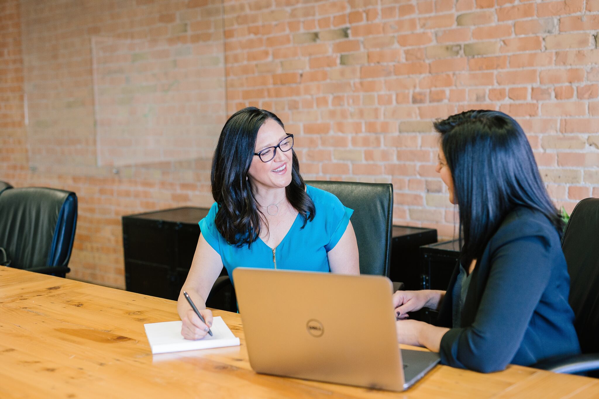 two women smiling and taking notes