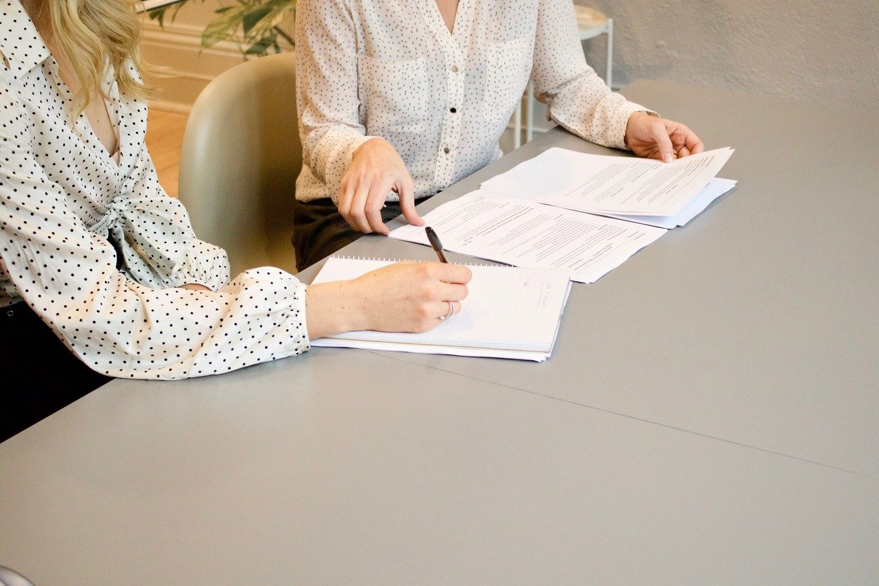 a woman signing on a paper and a woman next to her