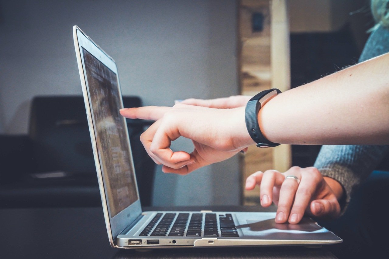 two people using a laptop and pointing at a screen