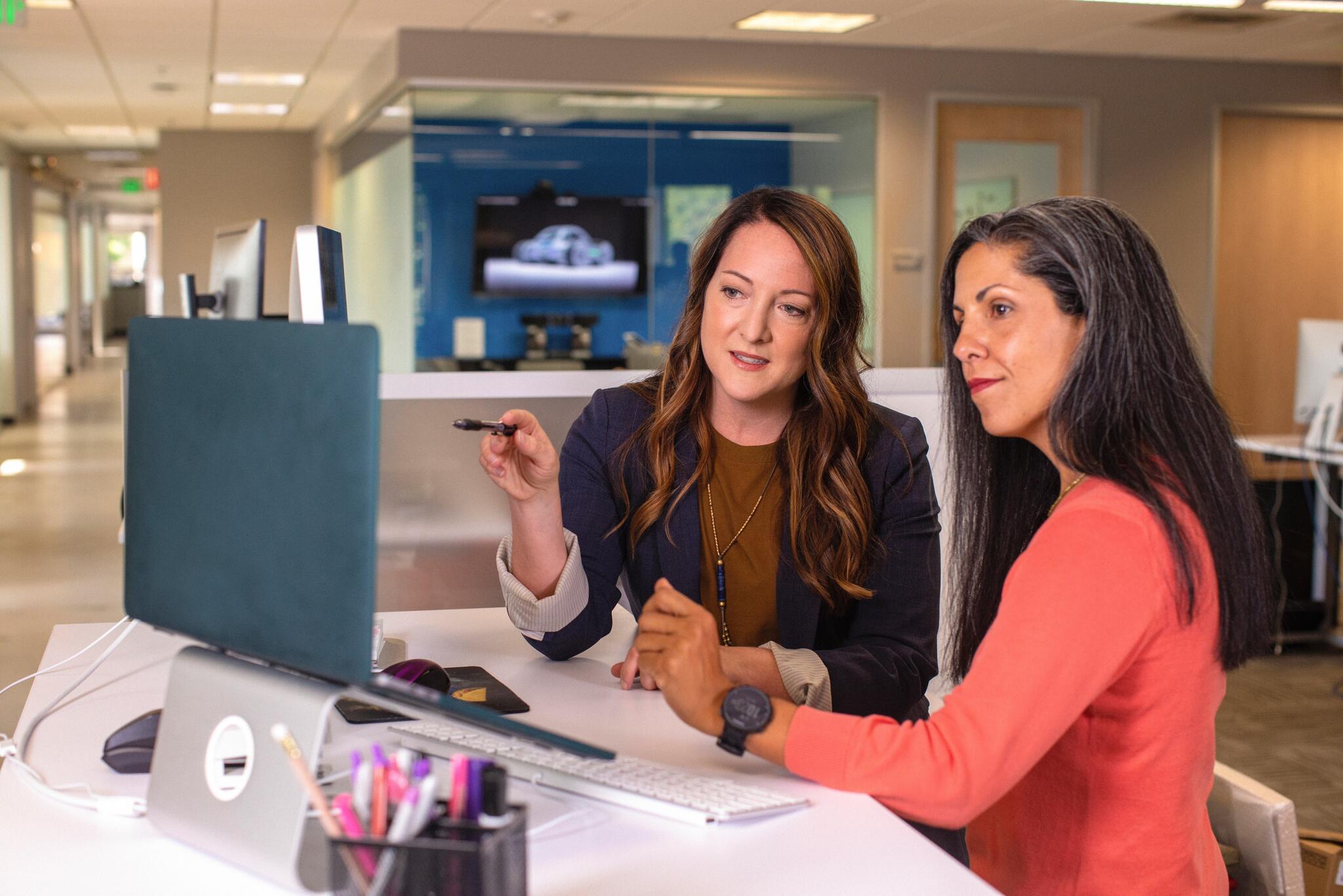 two women looking at a computer screen and talking