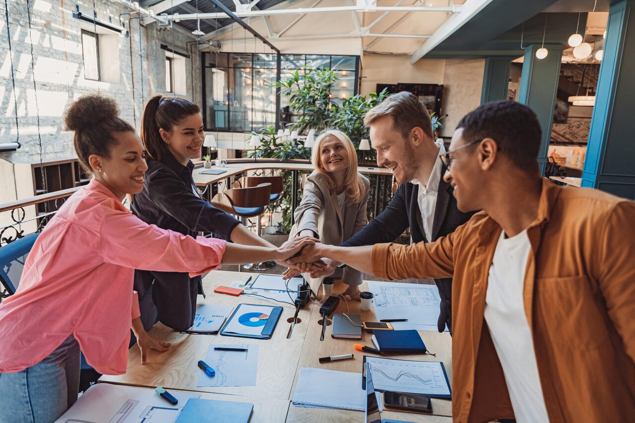 group of coworkers stacking hands together one in a meeting