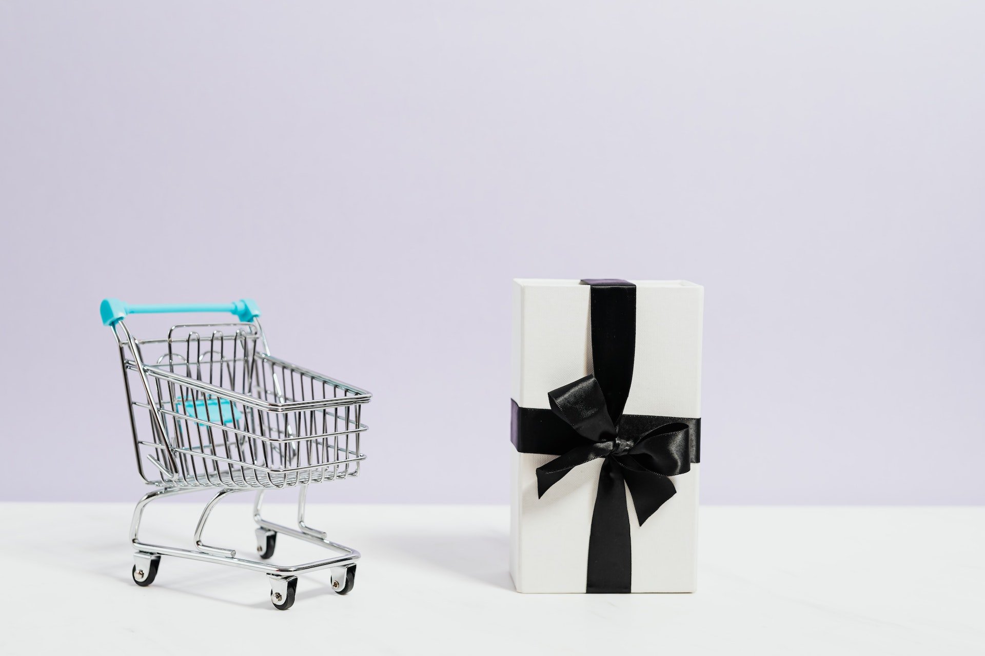 a shopping cart and a gift box with a lilac background