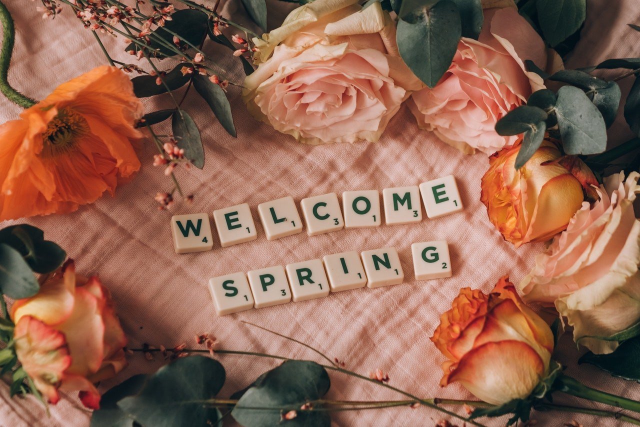 "welcome spring" written with Scrabble letters along with pink and orange roses