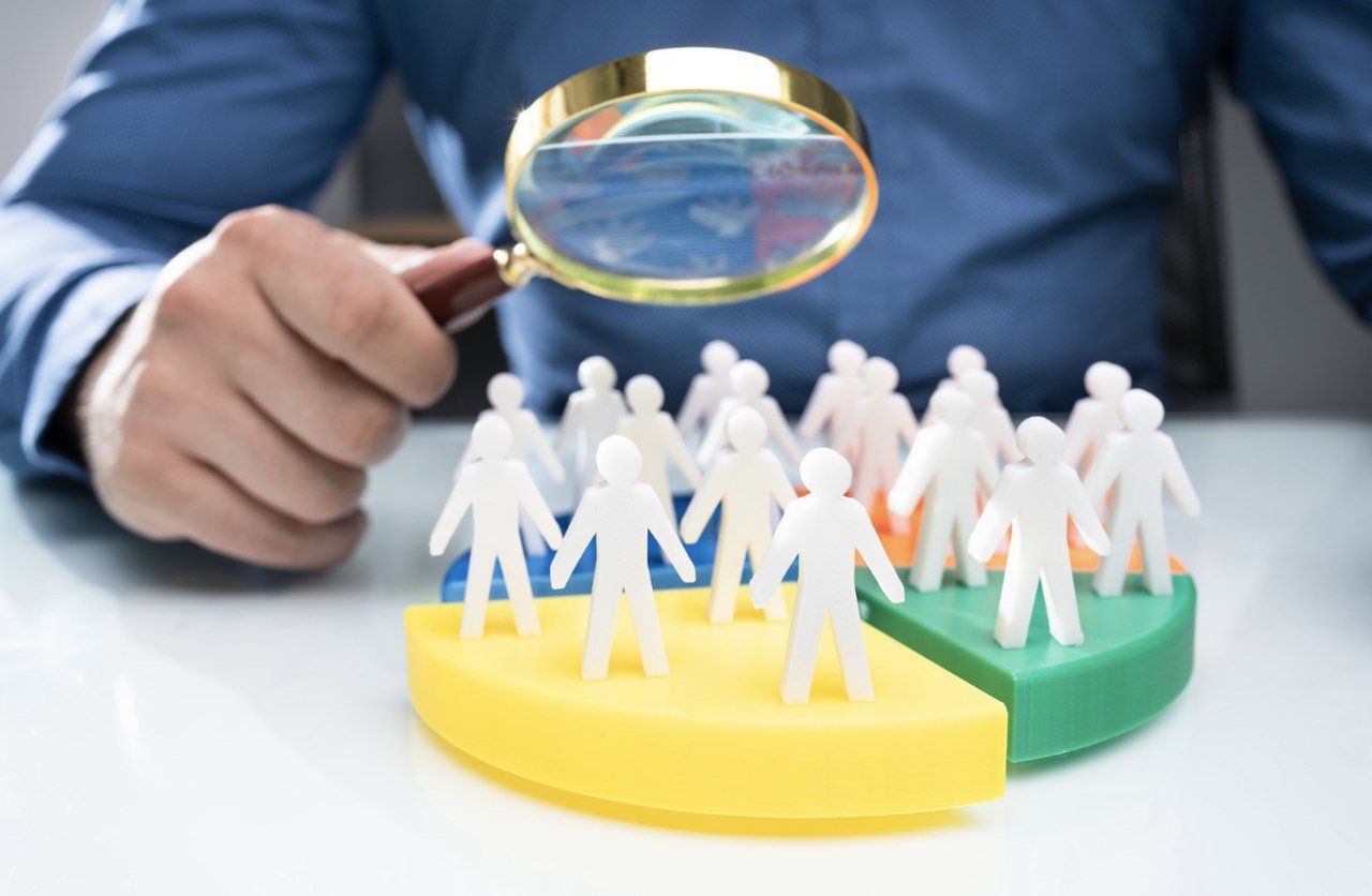 a picture of man's hand looking at a circle of people with magnifying glass