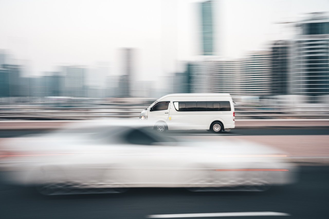 a white dodge driving so fast on the road that it can be barely seen