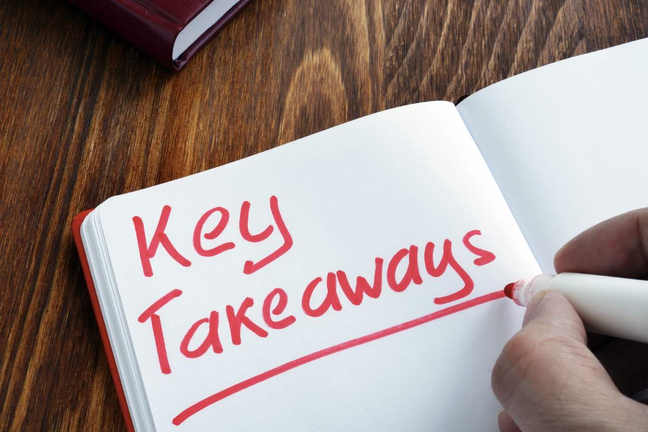 a picture of a hand writing with a red marker key takeaways in a notebook