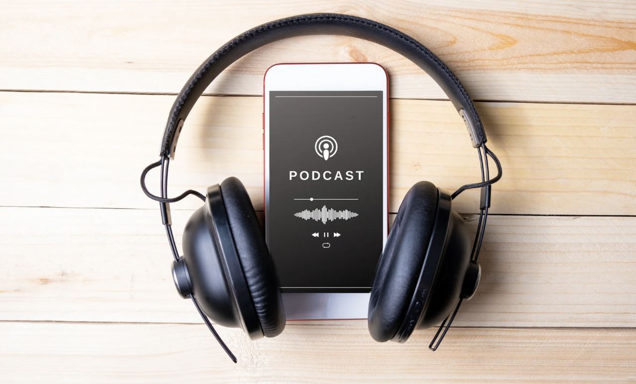 a picture of a black headphone with a smartphone in the center of it showing on its screen a podcast being played