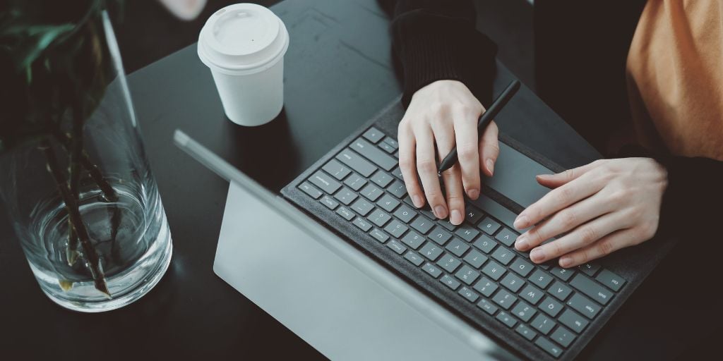 hands typing ona black laptop on a desk