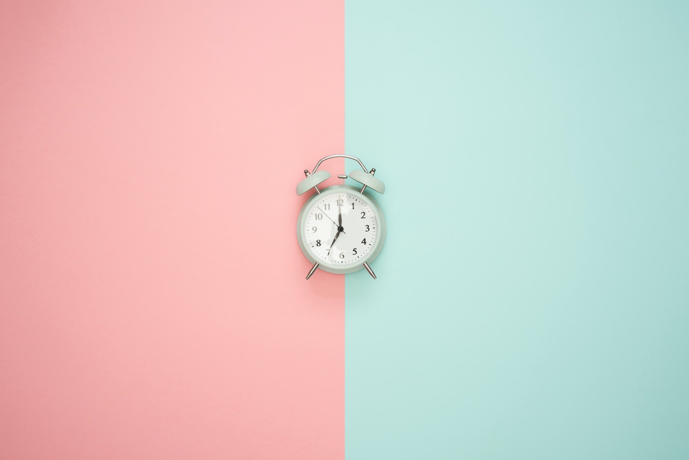 background divided into to; left is pastel pink and the right side is pastel light gree; there is a clock in the center