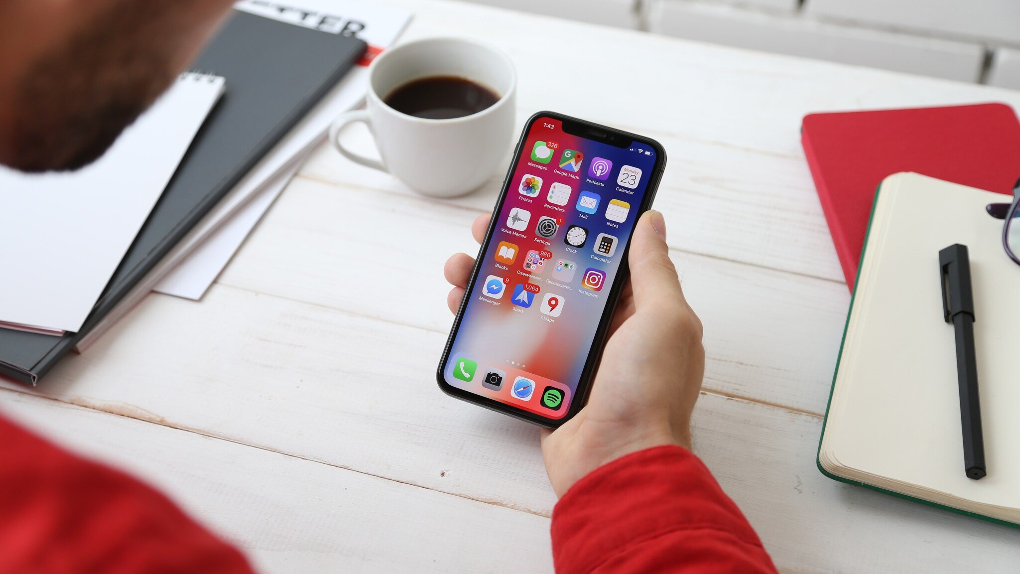 a hand displaying iPhone screen and coffee at the background