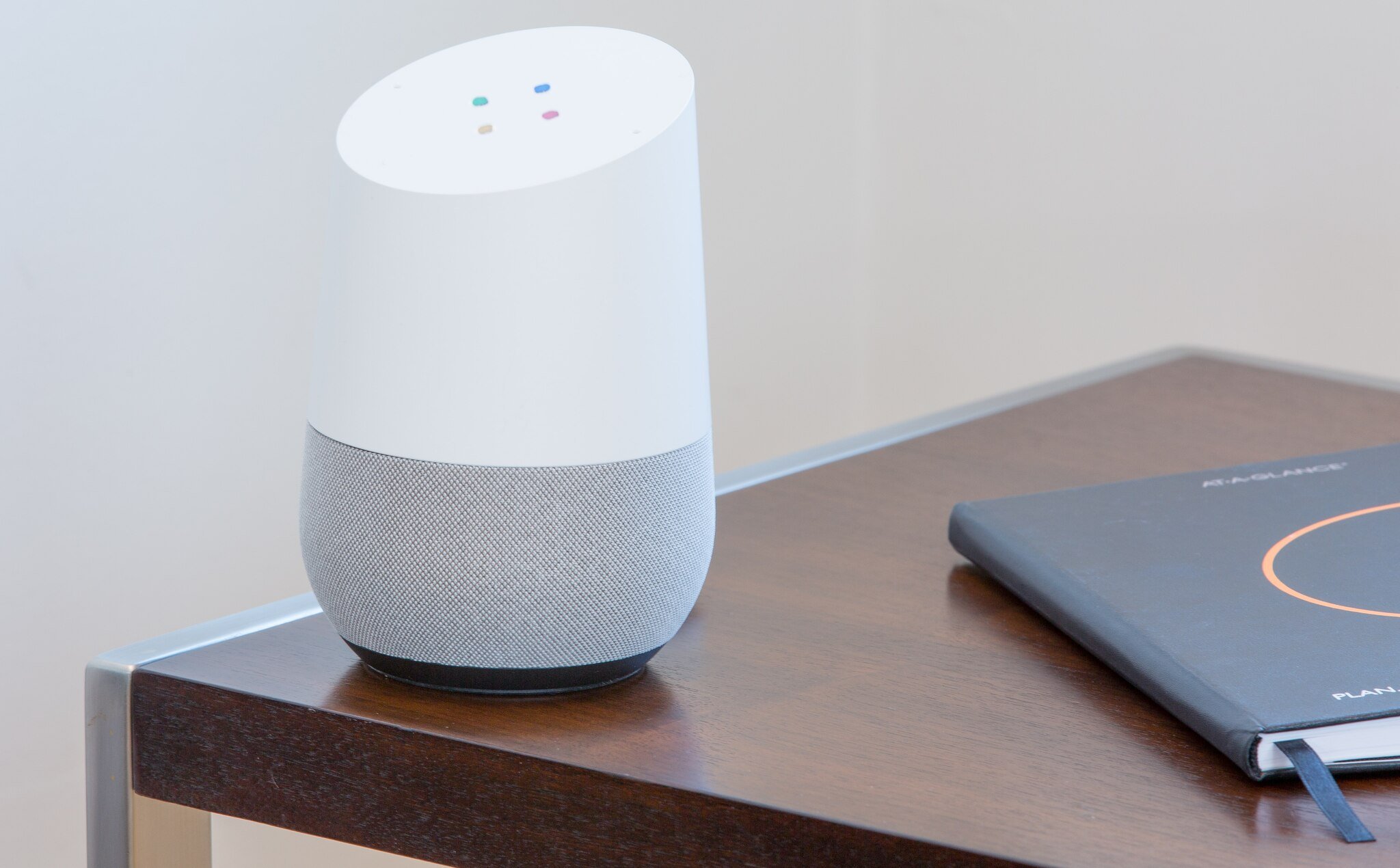 Google Assistant speaker on a table next to notebook