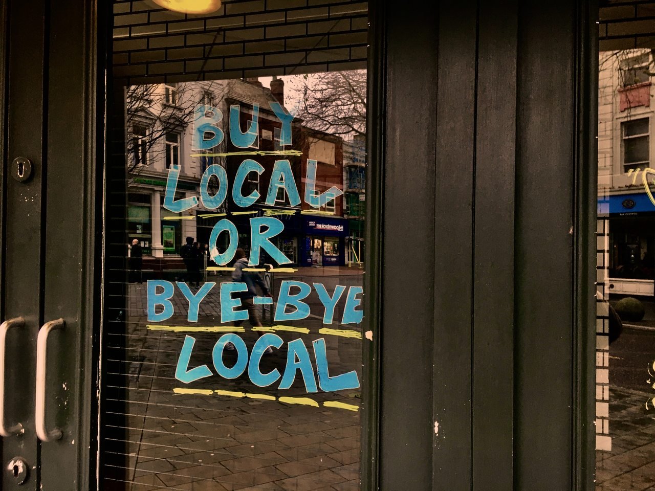 Blue "Buy Local or Bye-Bye Local door sign on a door