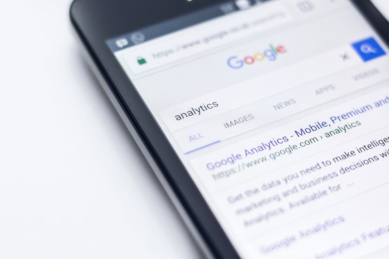 an image of a mobile phone showing the google search resault page for the keyword Analytics with the Google Analytic website on the first resault