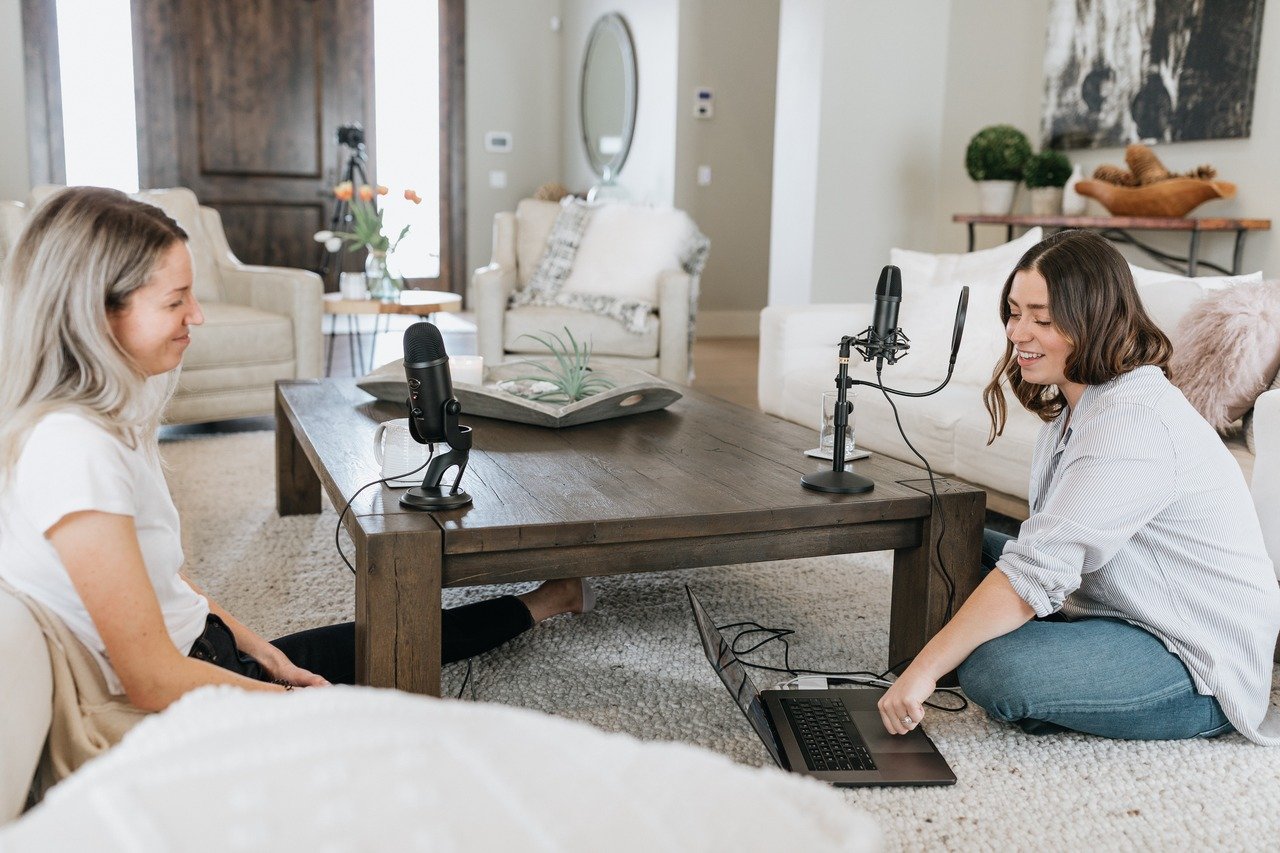 two women sitting in the living room anf preparing the microphone to make a recording