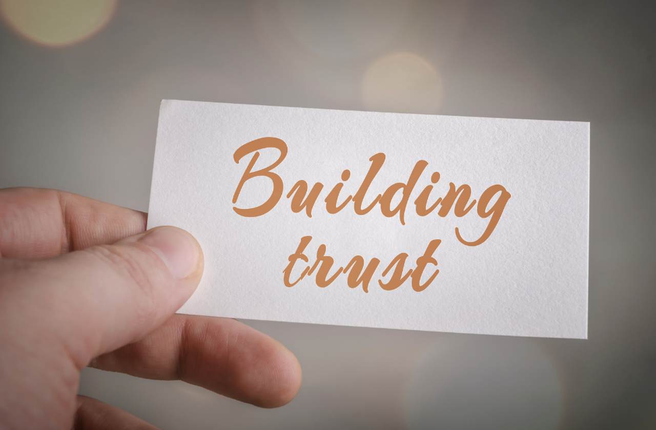 a picture of a hand holding a paper with a text written on it that says "building trust"