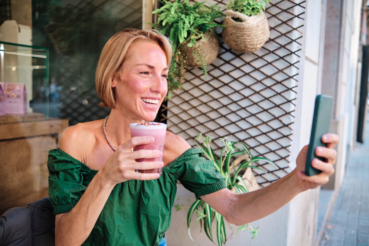 young woman using social media and drinking a healthy beverage