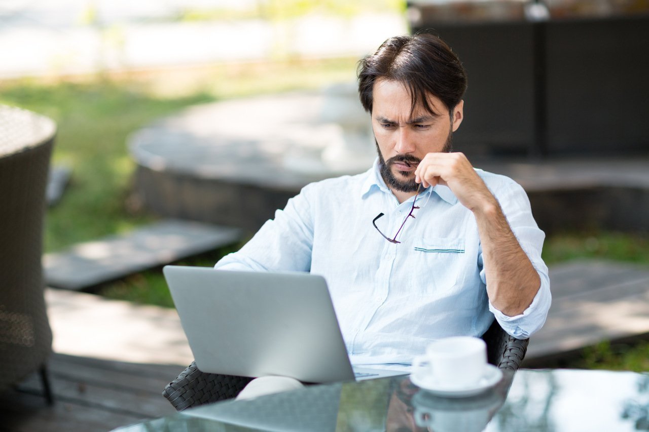 a man sitting and looking at his laptop thinking something