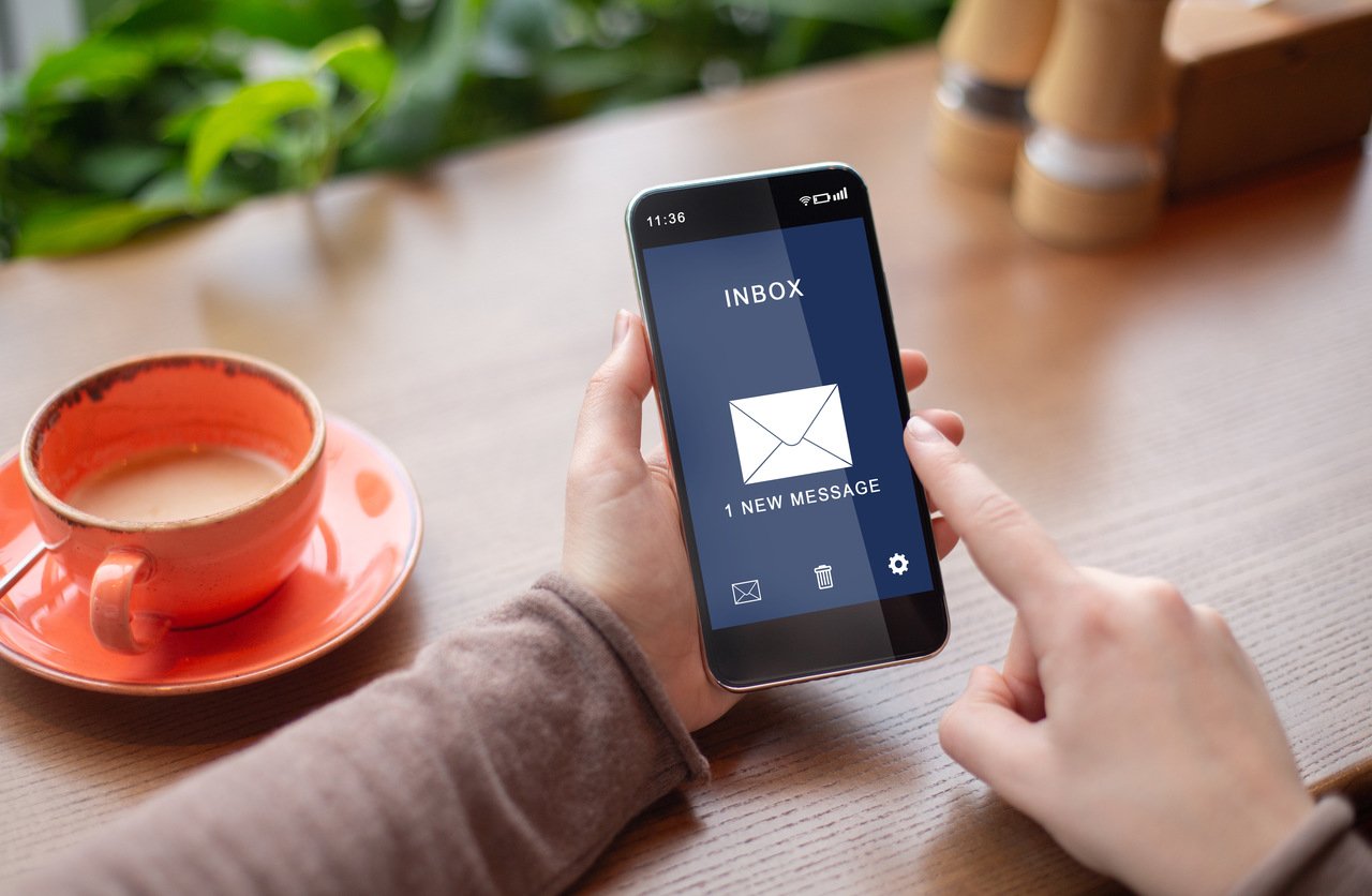 woman holding her mobile reading a new email message