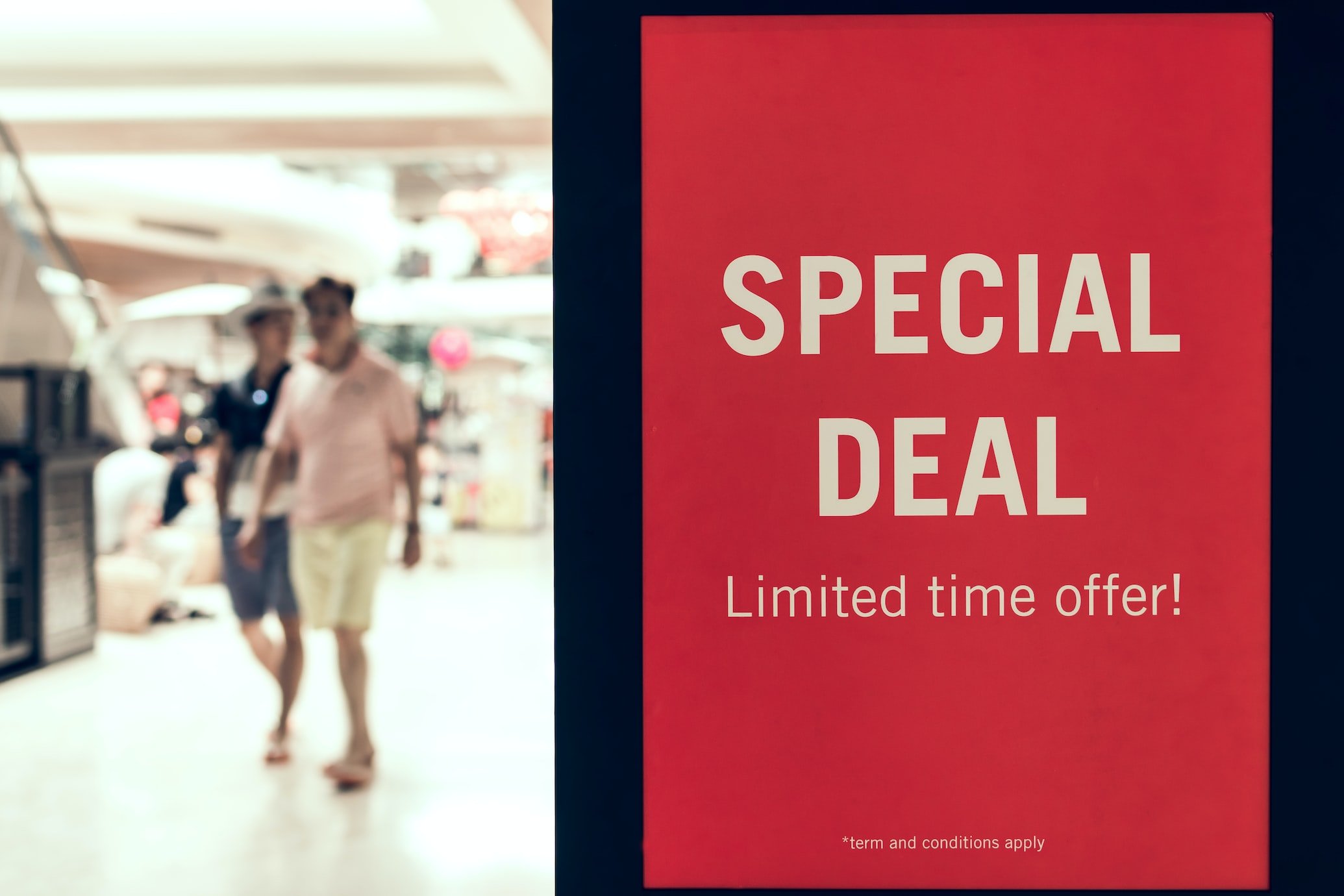 special discount offer banner on a red background an two people walking inside of a store on the left