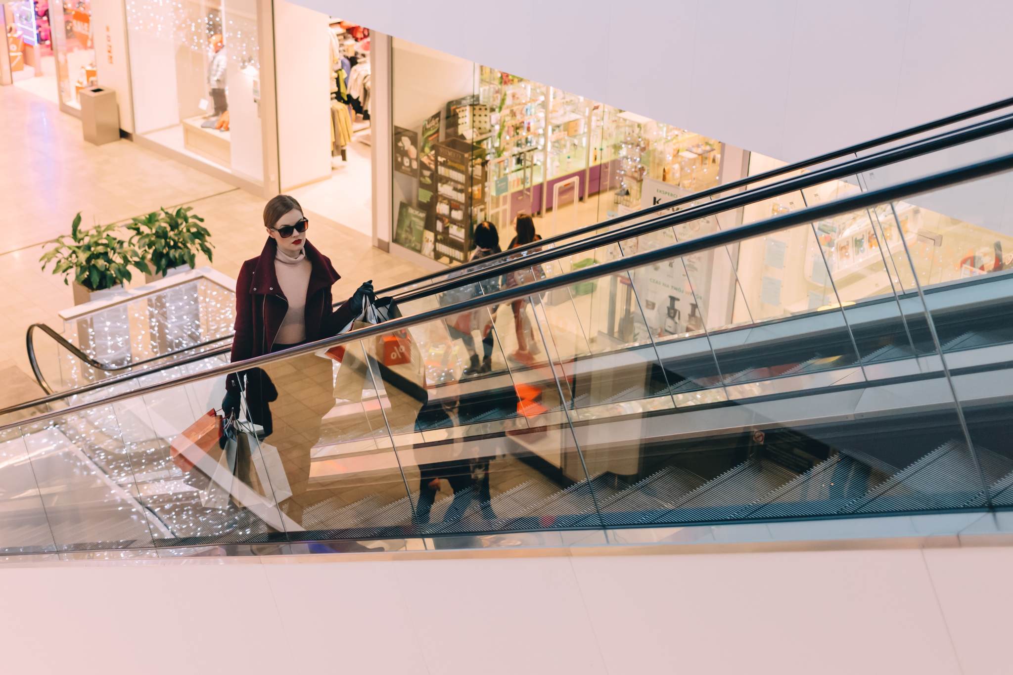 a woman with sunglasses in a shopping mall with shopping bags