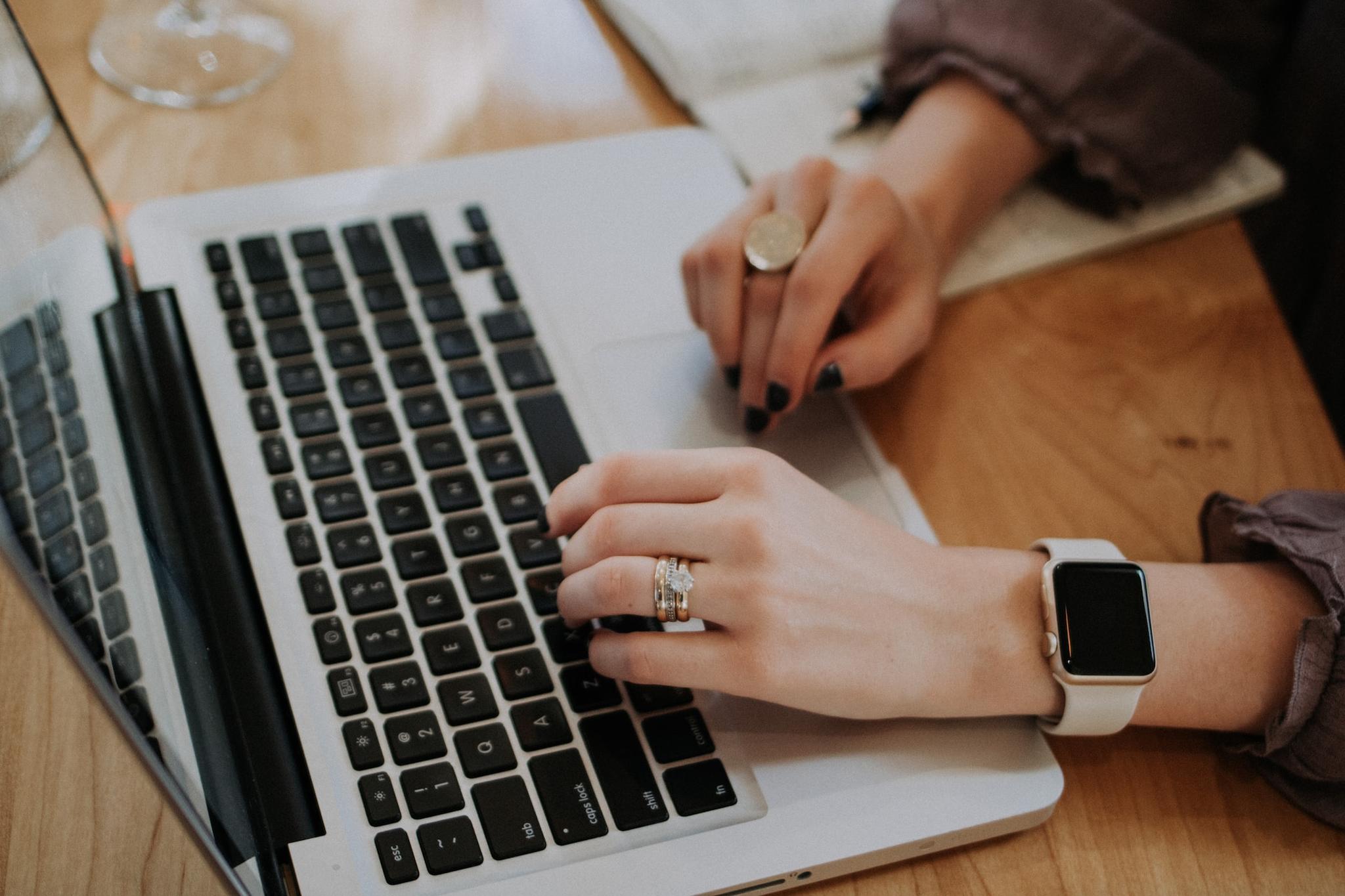 woman wearing rings writing on a MacBook