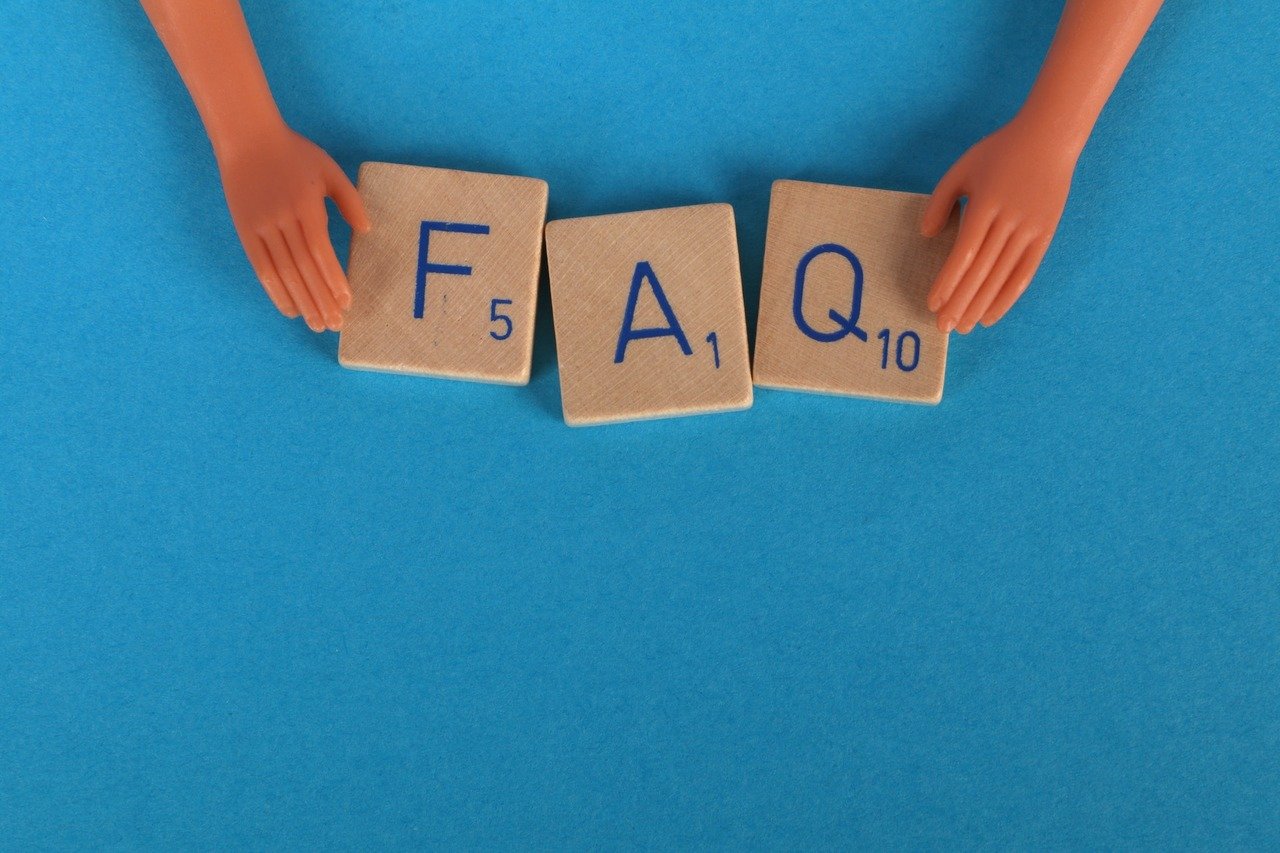 "FAQ" written with Scrabble and a doll's hands holding the letters