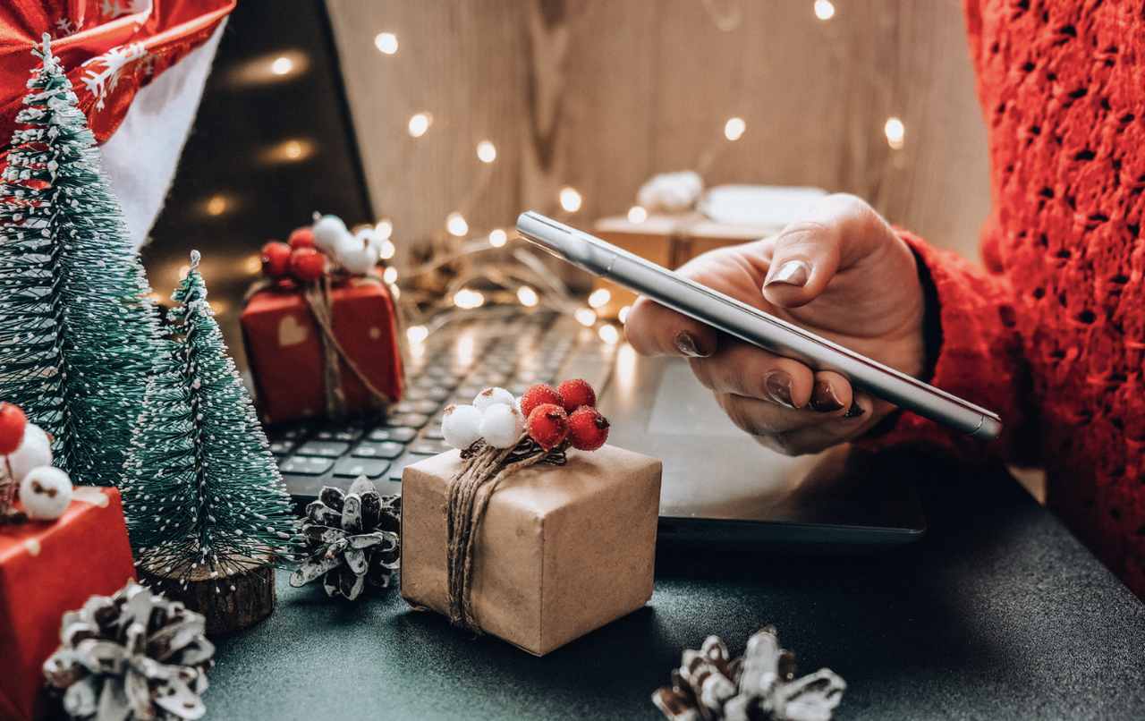 a hand working with a phone with christmas decoration around