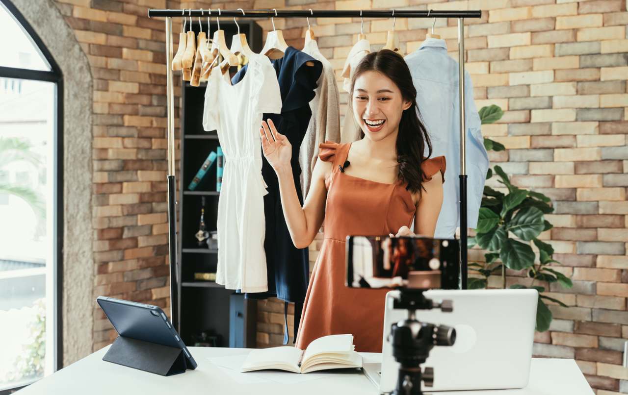 an influencer talking to her mobile camera and showing some products, clothes on her back to the followers