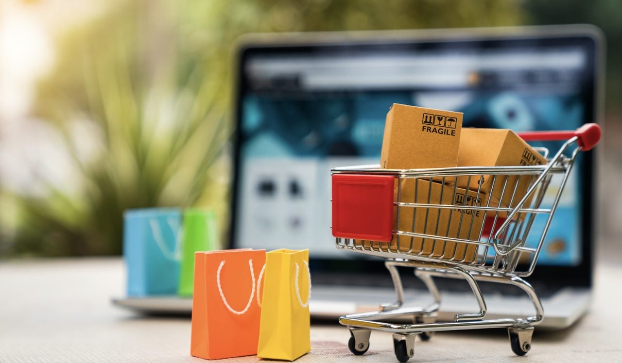 a mini shopping cart full of gift boxes and a laptop on the background