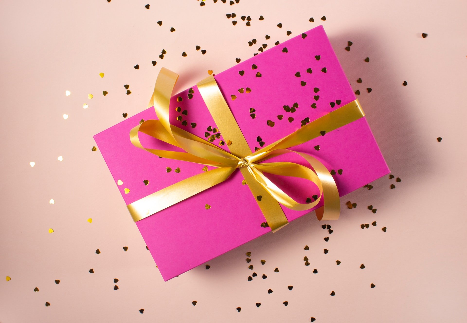 a pink gift box with a yellow ribbon