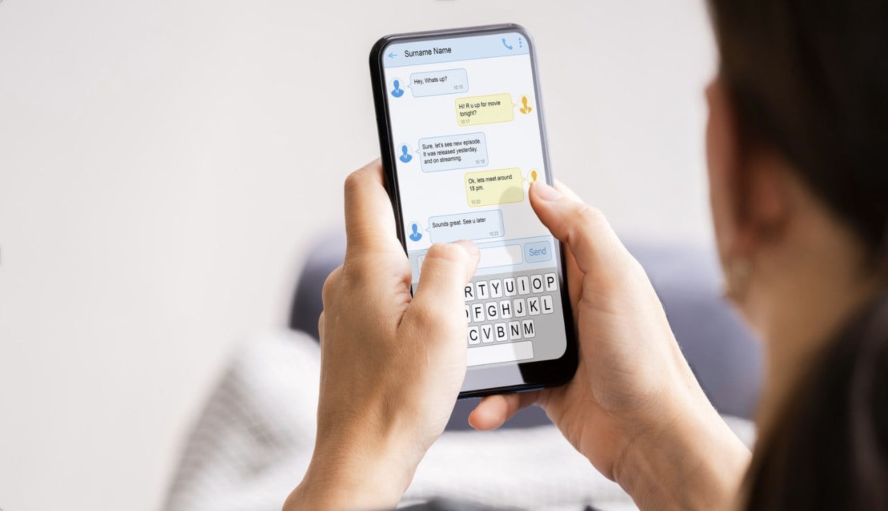 a girl holding a phone with both hands, checking her sms on an smartphone with her face partially visible