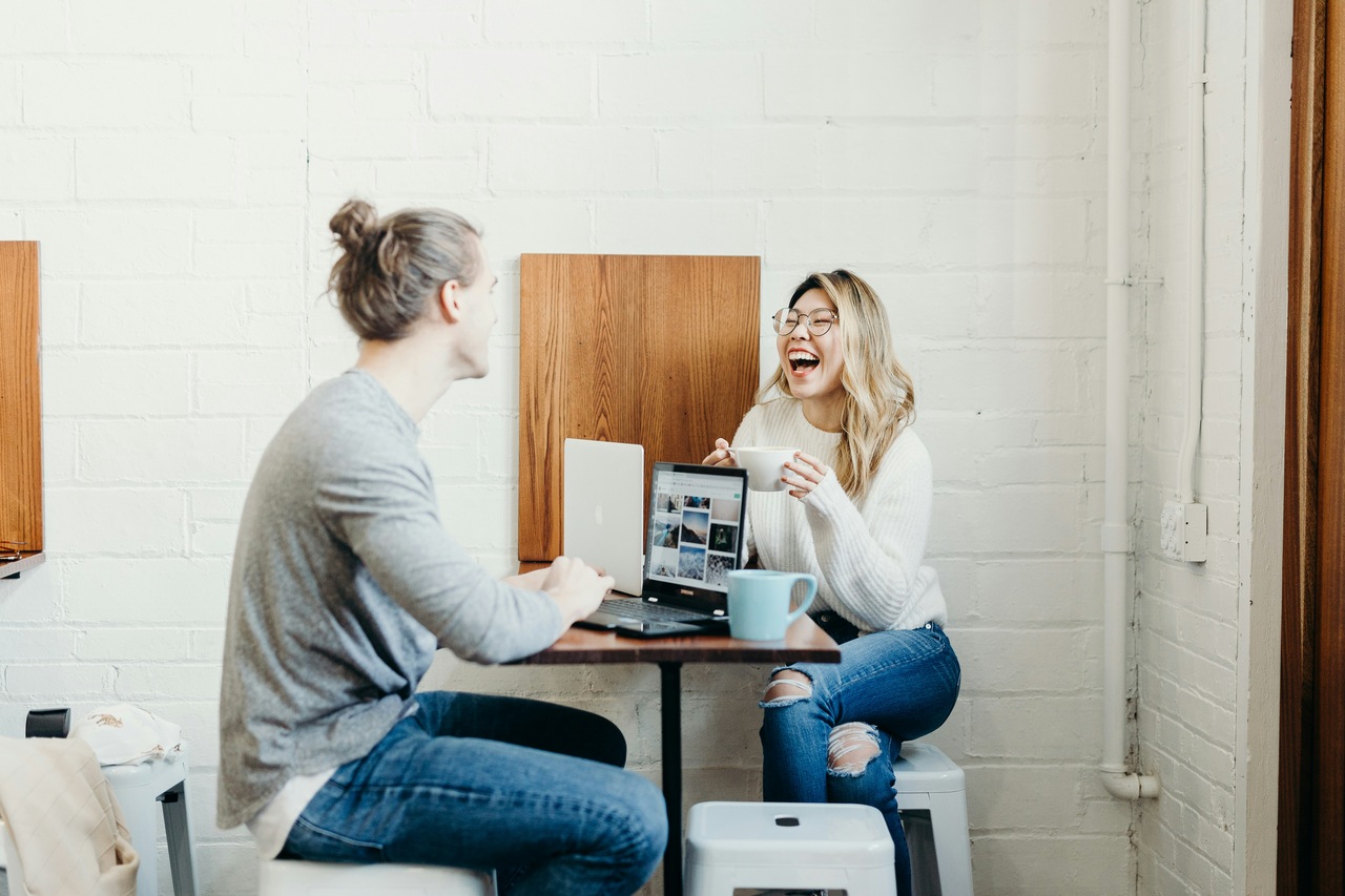 two people having a conversation, sitting, laughing, and writing